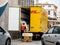 Senior worker discharge DHL parcels from truck in central square