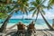 Seniors on summer vacation on the sea.Old elderly people sit in wooden shezlong and watch the sea. Back side view. Exotic plants