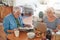 Seniors using a laptop and reading the newspaper over breakfast