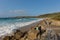 Sennon Cove beach Cornwall with people enjoying the blue sea and white waves