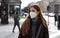 Sense of bewilderment. Young woman in winter clothes walking in street wearing protective mask FFP2 KN95. Girl with face mask