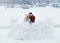 Sensitive full-length portrait of the cheerful laughing couple building the snowman in the village during the snow fall.