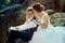 Sensitive portrait of the beautiful cheerful newlywed couple softly hugging on the rock.