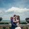 Sensitive romantic portrait of the beautiful happy newlyweds tenderly rubbing noses at the background of the view of the