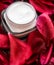 Sensitive skincare moisturizer cream on red flower petals and water background, natural science for skin