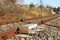 Sensor signaling the passage of the train on the railway track to activate the alarm at a road crossing. Mound of coarse gravel