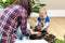 Sensory activities for child - young mother and son playing with dirt prepared for seeds. At home gardening and learning botany