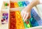 Sensory box with rainbow rice inside. Montessori material baby