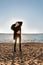 Sensual athletic fitness girl standing on the seashore in the glare of sunset rays in black clothes demonstrating the abdominal mu