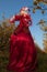 Sensual blond girl in fantasy red fairy tale stylization in apple park.