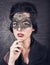 Sensual brunette with retro look and lace mask on black glowing