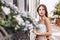 Sensual calm portrait of beautiful young woman in blooming bush with white flowers of petunias