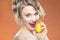 Sensual Caucasian Blond Girl Biting Yellow Lemon Fruit. Posing Against Orange Background.