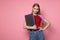 Sensual cheerful young woman standing against pink wall