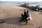 Sensual couple in love sitting on sand at the beach, hugging and talking, relaxing