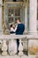 Sensual husband and wife hugging near balustrade in antique ruined palace. Back view