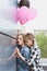 Sensual lesbian couple embracing and holding air balloons outdoors