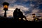 Sensual portrait of silhouette couple softly rubbing noses while sitting on the Chain Bridge near lightning street lamp