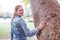 Sensual redhead woman touching tree and looking back in park