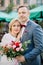 sensual romantic aged couple with flower bouquet, standing next to each other outside in city