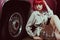 sensual stylish girl in red wig and stylish trench coat sitting
