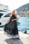 Sensual woman with blond hair in luxurious dress with accessories posing near yacht in dock