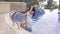 Sensual woman with dark hair in luxurious wedding dress posing near swimming pool