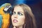 Sensual woman look at parrot. Woman with blue and yellow macaw. girl with makeup and bird pet. Beauty model with