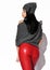 Sensual woman with perfect buttocks wearing tight red leather pants, grey pullover and hat stands with her back to camera