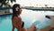 Sensual woman sit by tropical resort swimming pool