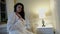 sensual woman is sitting alone in bedroom at evening, preparing to sleep, relaxing and dreaming