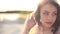 Sensual young brunette woman covering her face with a veil. Close-up shot. Summmer sunny beach background