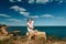 Sensual young couple in glasses in love jump on the rock in the sea near the beach with big cliffs. Man and woman looking on each