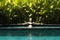 Sensual young woman relaxing in outdoor spa infinity swimming pool surrounded with lush tropical greenery of Ubud, Bali.