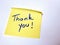 The sentence Thank you written by hand on a yellow post it