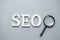 SEO Search Engine Optimization text and magnifying glass on gray background. Idea, Vision, Strategy, Analysis, Keyword and