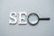 SEO Search Engine Optimization text and magnifying glass on gray background. Idea, Vision, Strategy, Analysis, Keyword and