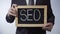 SEO written on blackboard, businessman holding sign, business concept, strategy