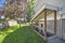 Separate basement apartment entrance with stairs, glass panel and trees on the lawn at the side