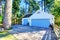 Separate garage with blue door and wooden driveway.