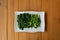 Seperate slided and boiled Chinese Thai KALE vegetable lay on the white rectangle on the wood table