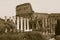 Sepia image of columns of the Forum and Colosseum or Roman Coliseum at dusk with streaked car lights, originally the Flavian