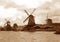 Sepia tone of three waterfront Dutch windmills under the cloudy sky, Netherlands