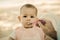 Sepia toned. Sad baby eats porridge, soiled and food in the nose. Dad feeds little daughter with a plastic spoon. Against the