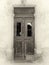 Sepia view of a broken old double doors a traditional abandoned spanish house with broken windows and faded peeling paint