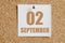 September 02. 02th day of the month, calendar date.White calendar sheet attached to brown cork board.Autumn month, day of the year