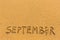 September - word inscription on the gold sand beach.