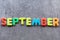 September word written with colorful letters on grey granite stone background