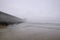 Serene beach scene features a tranquil shore with wet sand, in fog