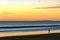 Serene beach sunset view of the California coast with silhouette of lone jogger.